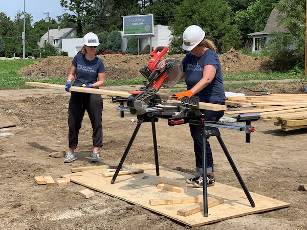 OrthoNebraska employees work with a band saw while building a house with Habitat for Humanity.